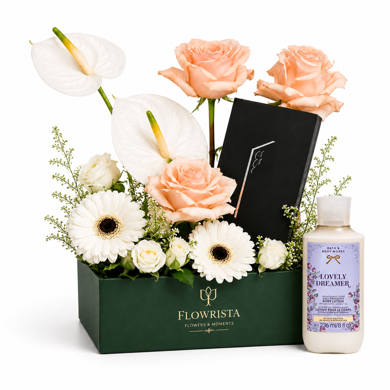 A curated gift set featuring a dark green box of flowers from Flowrista, including peach roses, white anthuriums, daisies, and a black card, alongside a bottle of 'Lovely Dreamer' body wash by Dr. Brand.
