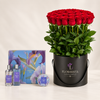 A large gift set featuring a vibrant bouquet of 60 red roses in a black round bucket with the brand name 'FLOWRISTA' printed on it, accompanied by a matching blue floral gift box and two small perfume bottles labeled 'EIFFEL MONT BLANC'.