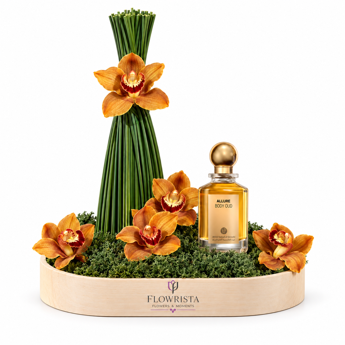 A luxury orchid flower arrangement in a light wood tray with a matching glass perfume bottle. The arrangement features vibrant orange orchids and tall green stems on a bed of green moss, set in a circular wooden tray branded 'FLOWRISTA'.