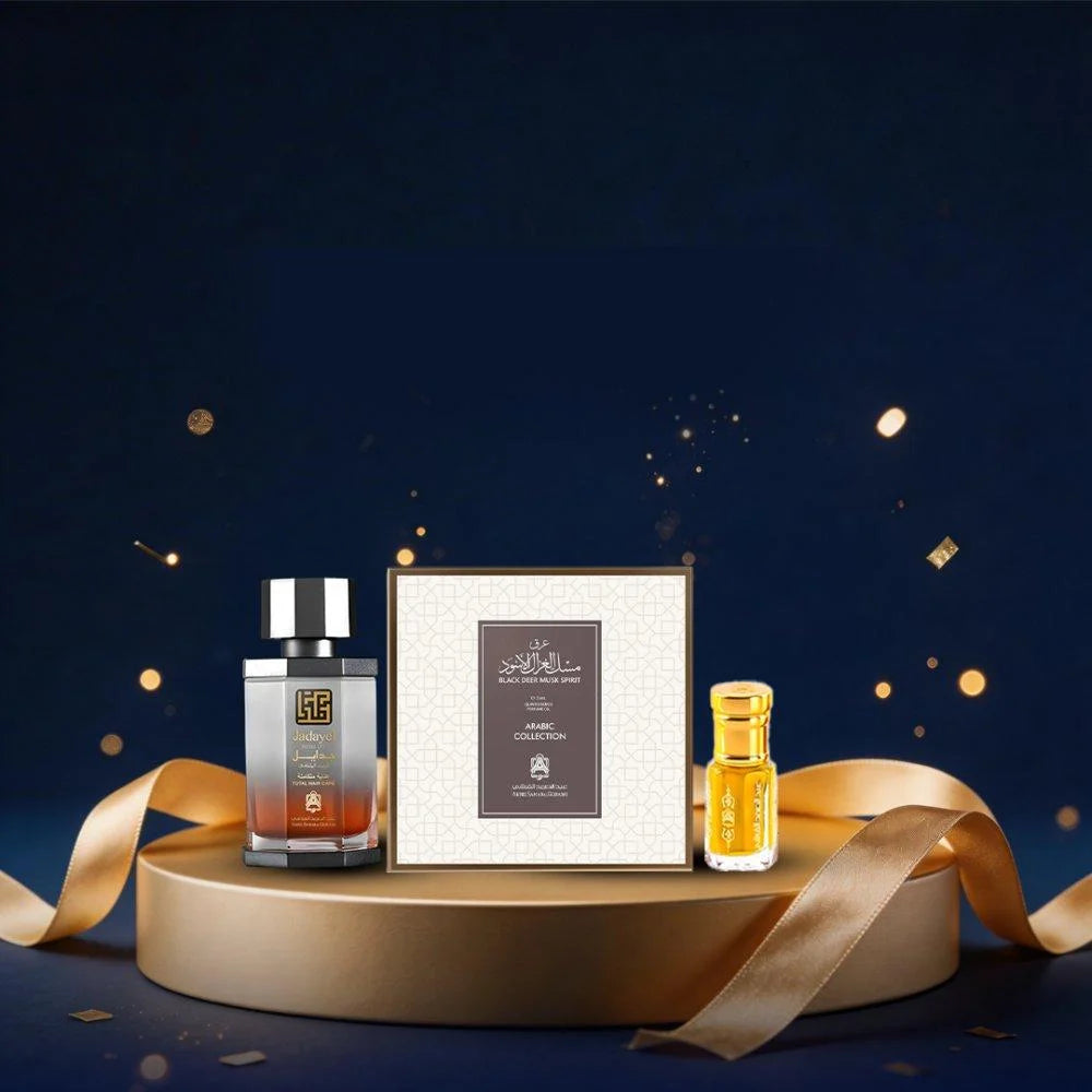 A luxury fragrance gift set featuring a dark glass bottle with a silver cap, a small yellow perfume bottle, and a textured cream-colored box, arranged on a round gold pedestal with a gold ribbon against a dark blue background with gold confetti.