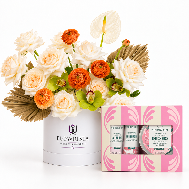 A floral gift arrangement in a white round box from Flowrista, featuring cream and orange flowers with green leaves, displayed next to a pink and cream 'The Body Shop' British Rose body butter and bath bomb gift set on a white background.