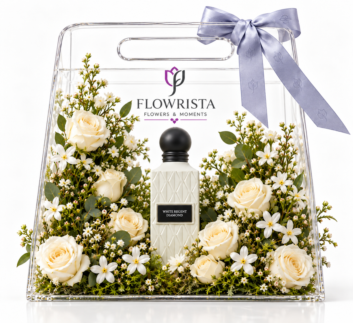 A clear acrylic gift box with a handle, tied with a lavender ribbon, containing a bottle of Flowrista 'White & Bright Vanilla' perfume surrounded by cream roses, white flowers, and green foliage on a white background.