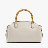 An off-white leather handbag with a distinctive curved bamboo handle, shown against a plain white background.