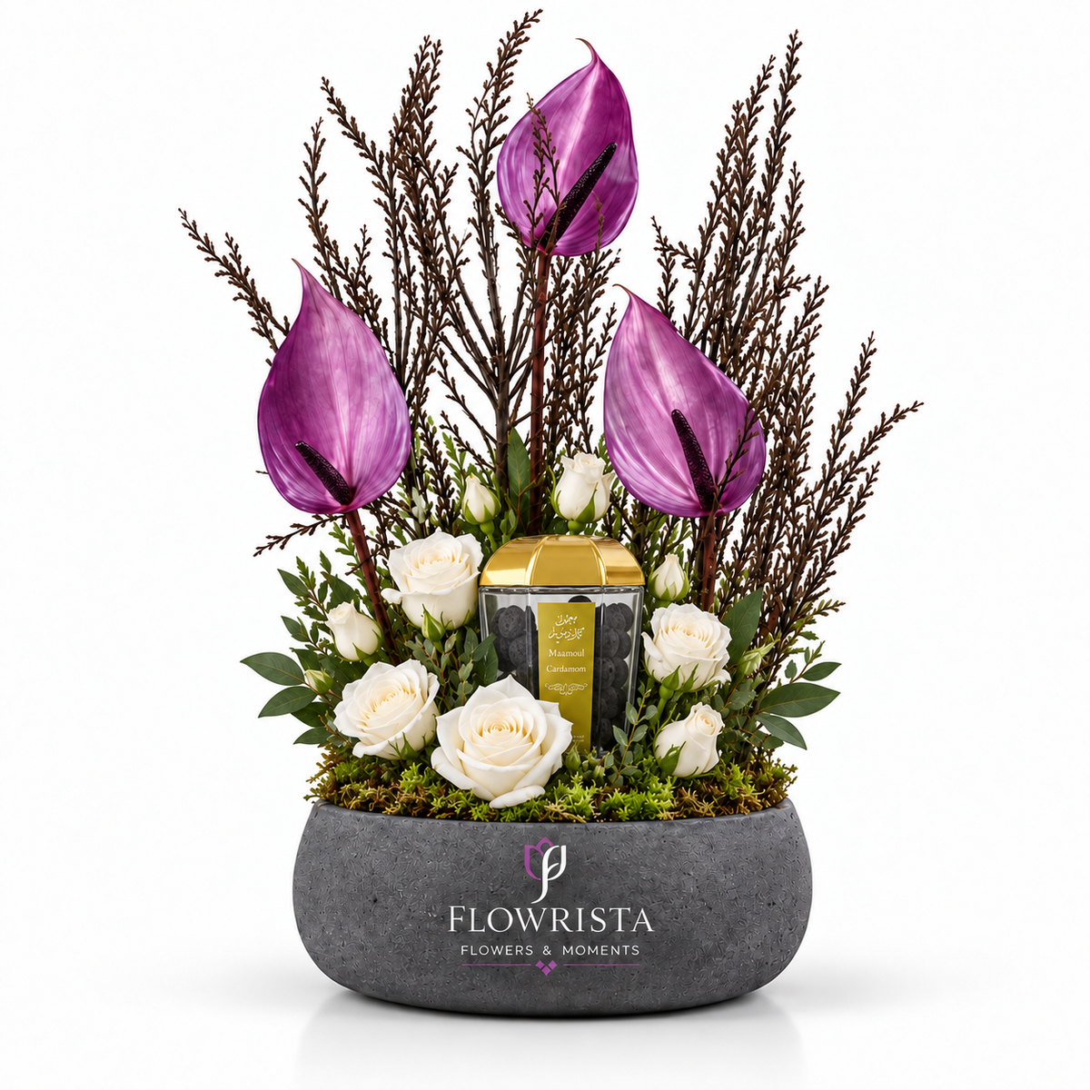 A floral arrangement in a gray stone-style pot by Flowrista, featuring purple anthuriums, white roses, green foliage, and a small gold-and-black candle, photographed on a clean white background.