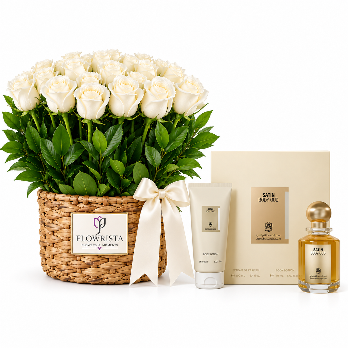 A luxury gift set featuring a large basket of white roses with green leaves, a woven basket, a cream satin body oil box, a white body lotion tube, and a small satin body oil bottle with a gold cap on a white background.
