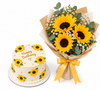 A white birthday cake decorated with sunflower motifs and the words 'Happy Birthday' on top, shown next to a matching bouquet of large yellow sunflowers, white filler flowers, green eucalyptus leaves, and a gold ribbon on a white background.