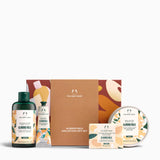 The Body Shop Almond Milk Collection Gift Set featuring a brown cardboard gift box, a dark green shower gel bottle, a hand and foot wash bottle, a soap bar, and a round body butter tin, all arranged on a white background.