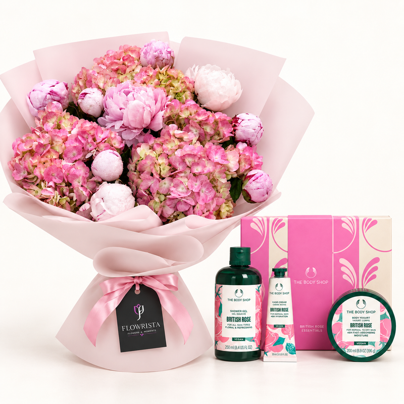 A curated gift set featuring a large bouquet of pink and white hydrangeas wrapped in pale pink paper, alongside The Body Shop British Rose body care products including a bottle, tube, and jar, with their branded pink packaging boxes.