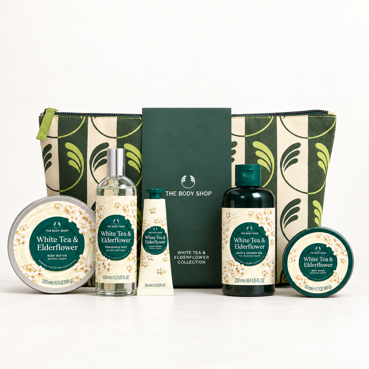 The Body Shop White Tea & Elderflower gift set featuring a green and cream patterned zip pouch, a dark green card, a hand cream tube, a shower gel bottle, a bath bomb tin, and two body butter tins on a white background.