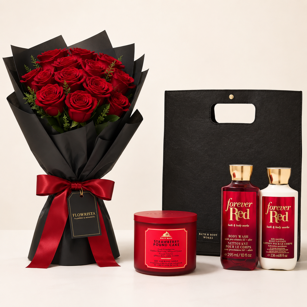 A Valentine's Day gift set featuring a bouquet of 24 red roses in black wrapping with a red ribbon, a Bath & Body Works 'Forever Red' body wash bottle, a body lotion bottle, and a Strawberry Punch bath bomb jar, alongside a black gift bag.