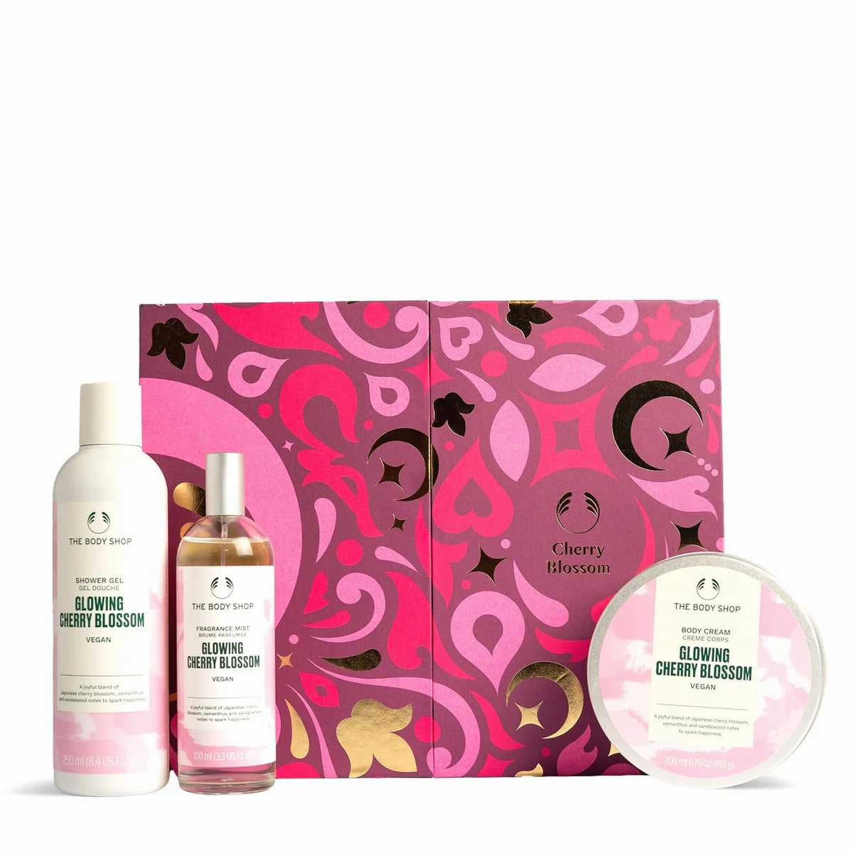 The Body Shop Cherry Blossom body care gift set featuring a shower gel bottle, a body wash bottle, and a round body butter dish arranged in front of a decorative pink and magenta gift box on a white background.