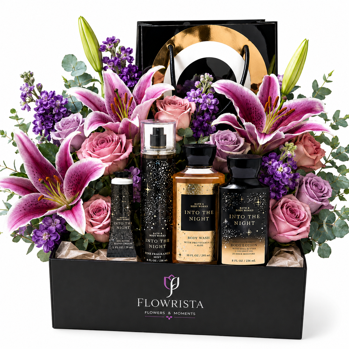 A luxury gift set from Flowrista featuring a vibrant floral arrangement with pink lilies, purple flowers, and roses in a black box, styled with three body wash bottles ('Into the Night' in black, gold, and dark purple) and a black gift bag with a gold circular emblem.