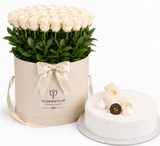 A gift set featuring a round box of 100 cream roses with green stems, presented in a beige cylindrical container with a satin bow, alongside a white frosted cake decorated with cream and a chocolate piece. The brand 'FLOWRISTA.
