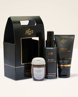 Men's grooming products including a cologne, body wash, and body cream in front of a branded box.