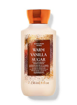 A bottle of Bath & Body Works Warm Vanilla Sugar body lotion with a warm cream-colored body, a dark brown label, and a metallic copper-orange cap, set against a plain white background.