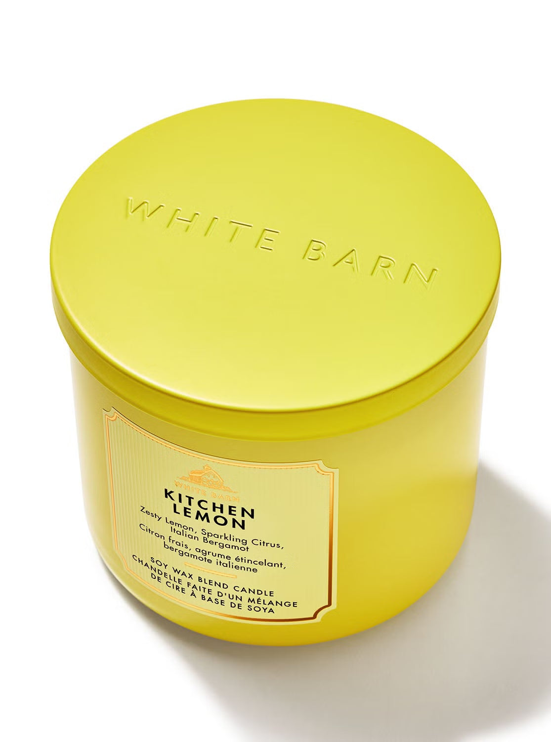 A bright yellow White Barn 'Kitchen Lemon' soy wax candle in a matching yellow metal tin with a matching lid, set against a clean white background.