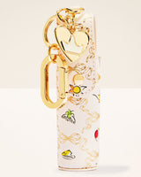 A white leather keychain pouch with a gold-tone heart-shaped charm, gold keyring, and a tropical-themed print featuring palm trees, a sun, and small colorful illustrations.