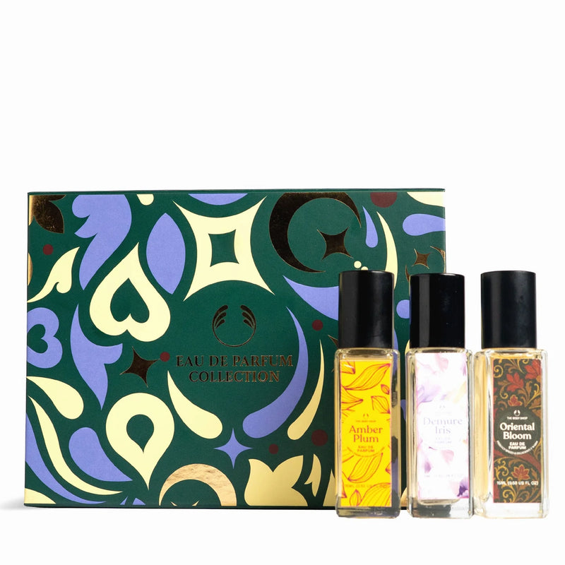 A fragrance gift set featuring a decorative green box with abstract gold and purple patterns, alongside three small perfume bottles labeled Amber Plum, Oriental Bloom, and Sensuous Pink on a white background.