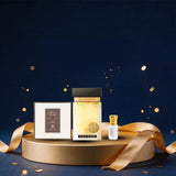 A perfume gift set displayed on a round gold pedestal against a dark navy background with gold bokeh and confetti. The set includes a rectangular box with Arabic text and a square glass bottle containing pale golden liquid, alongside a small clear vial with a gold cap.