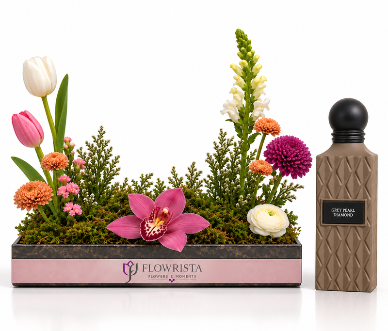 A floral arrangement in a rectangular pink and dark gray planter by Flowrista, displayed next to a textured brown bottle labeled 'Grey Pearl Diamonds' on a clean white background.