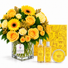 A floral gift set for Amber Plum by Flowrista, featuring a large yellow and white flower bouquet in a glass vase, two amber-colored fragrance bottles with silver caps, and a round tin of body butter, arranged in front of a yellow illustrated gift box on a white background.
