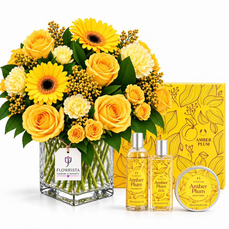 A floral gift set for Amber Plum by Flowrista, featuring a large yellow and white flower bouquet in a glass vase, two amber-colored fragrance bottles with silver caps, and a round tin of body butter, arranged in front of a yellow illustrated gift box on a white background.