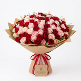 Red and pink rose bouquet in brown wrapping paper tied with ribbons and a Flowrista flower tag