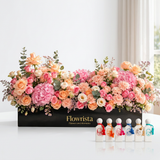 Mini Summer Collection six perfume bottles beside a pastel flower arrangement in a black Flowrista box