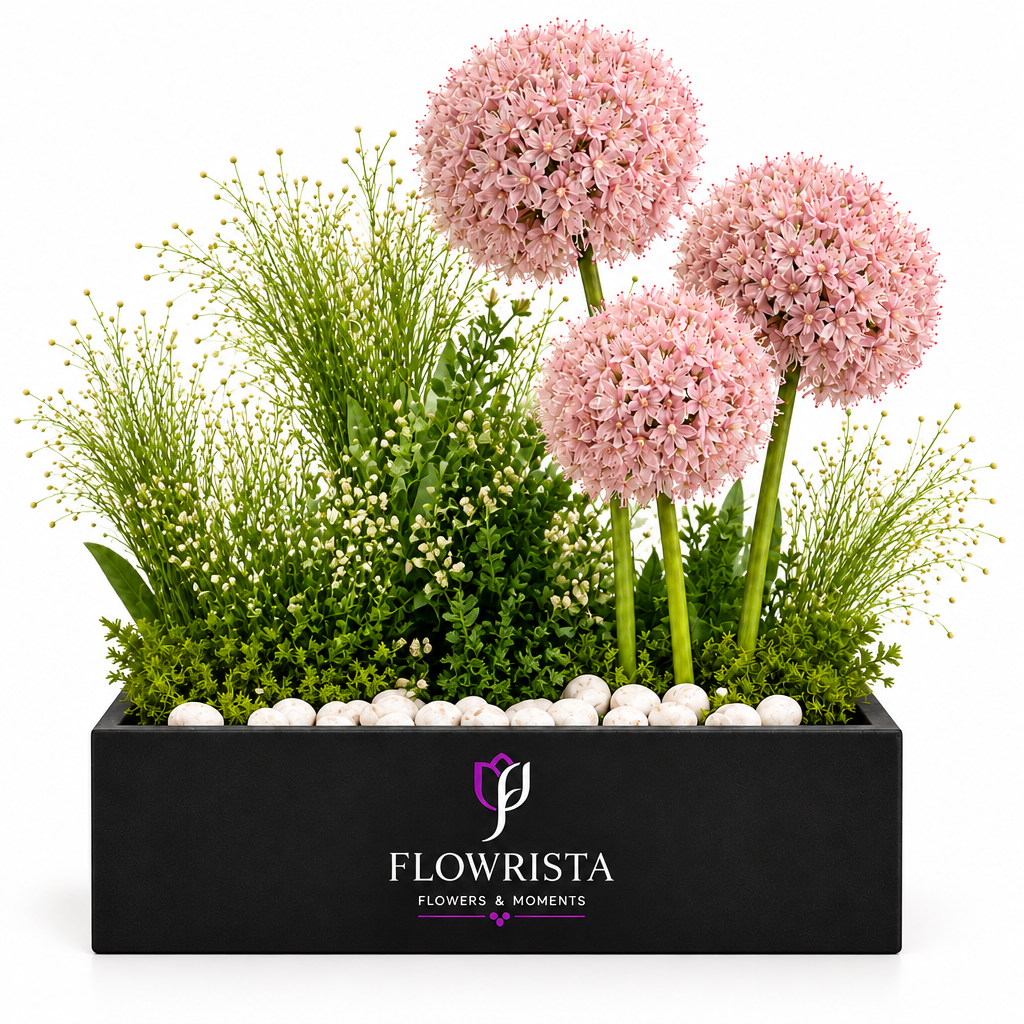 Pink allium flower arrangement with greenery and white pebbles in a black Flowrista planter