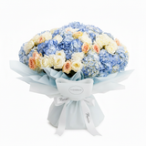 Flowrista blue hydrangeas peach and white roses bouquet in light blue wrapping on white background