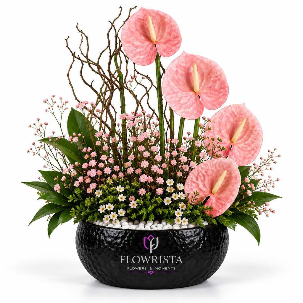 Artificial pink anthurium flower arrangement with white pebbles and greenery in a black Flowrista bowl