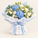Flowrista bouquet of blue hydrangeas, white roses and eucalyptus wrapped in pale blue and white