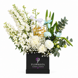 White and pale blue flowers in a black Flowrista box with gold Arabic get-well topper