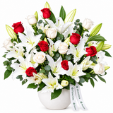 Flowrista red and white roses with white lilies and greenery in a rounded white pot