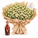 Asser perfume beside Flowrista white daisy bouquet with yellow centres in tan kraft wrapping