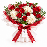 Red roses and white hydrangeas in Flowrista red and white wrap with red bow