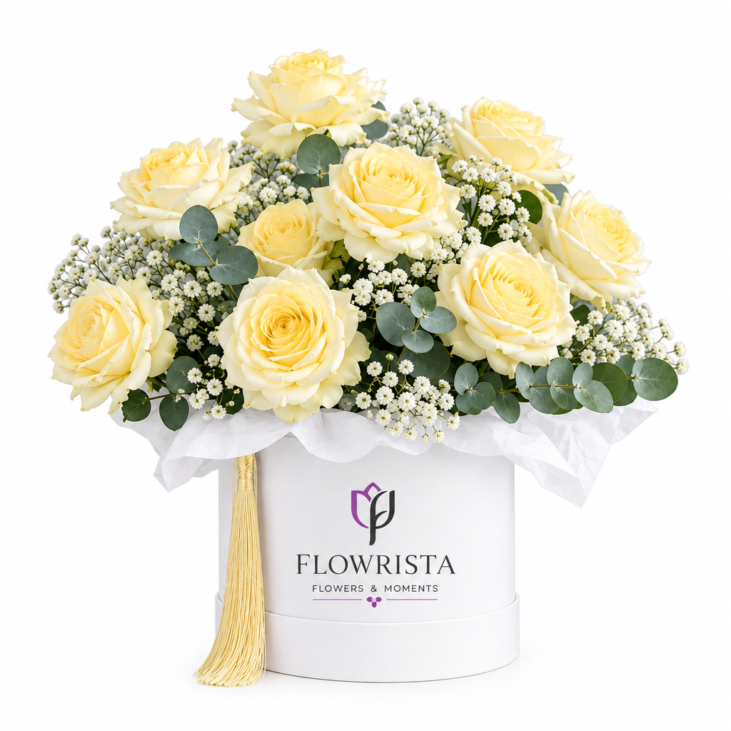 Cream roses baby's breath and eucalyptus in a white Flowrista hatbox with gold tassel