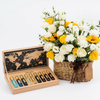 Tobacco Collection perfume set beside a Flowrista basket of white and yellow roses, lisianthus and sunflowers