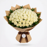 White rose bouquet with greenery in brown wrapping tied with a dark brown ribbon and Flowrista tag