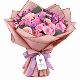 Pink blush and lavender roses in gold-edged pink wrapping with lavender bow and Flowrista tag
