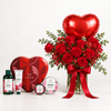 The Body Shop Valentine's Day gift set featuring a heart-shaped red tin, shower gel, hand cream, body butter, and a jar of lip balm, arranged next to a large bouquet of red roses with a red heart-shaped foil balloon in a glass vase.