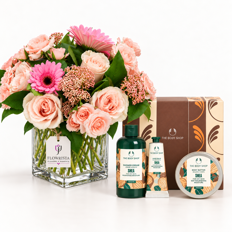 A curated gift set featuring a vibrant flower bouquet in a clear glass vase, alongside The Body Shop body care products including shower cream, hand cream, and a tin of shea, set against a clean white background.