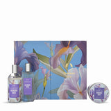 The Denure 'Iris' gift set featuring a large floral box, a small spray bottle, a travel spray bottle, and a round tin, all decorated with purple and white iris flowers on a light blue background.