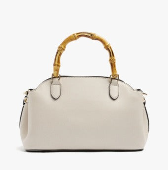 An off-white leather handbag with a distinctive curved bamboo handle, shown against a plain white background.