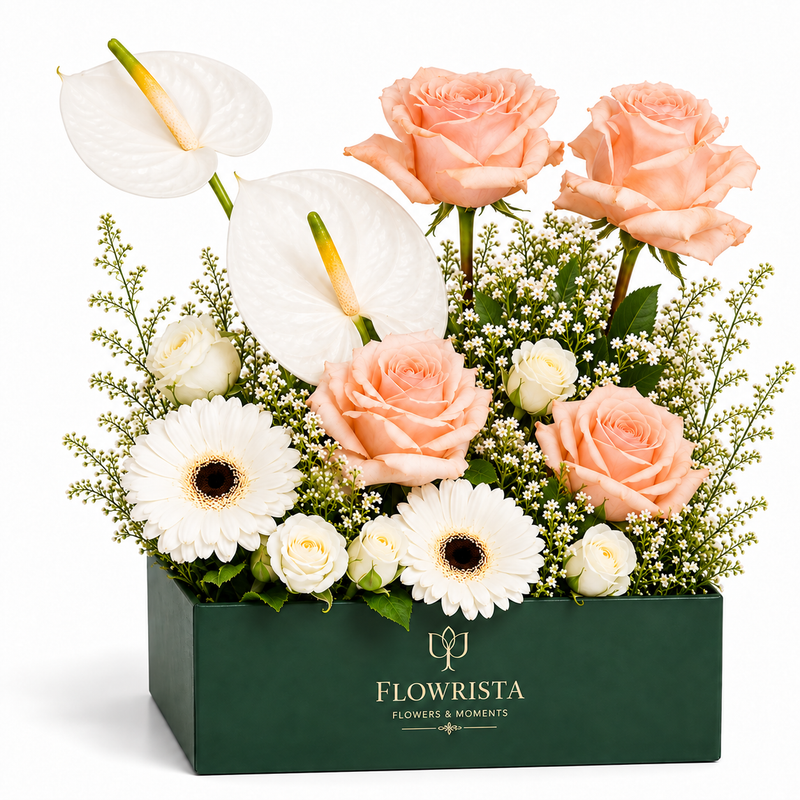 A floral arrangement in a dark green rectangular box from Flowrista, featuring peach roses, white anthuriums, white gerbera daisies, small white roses, and green filler flowers on a clean white background.