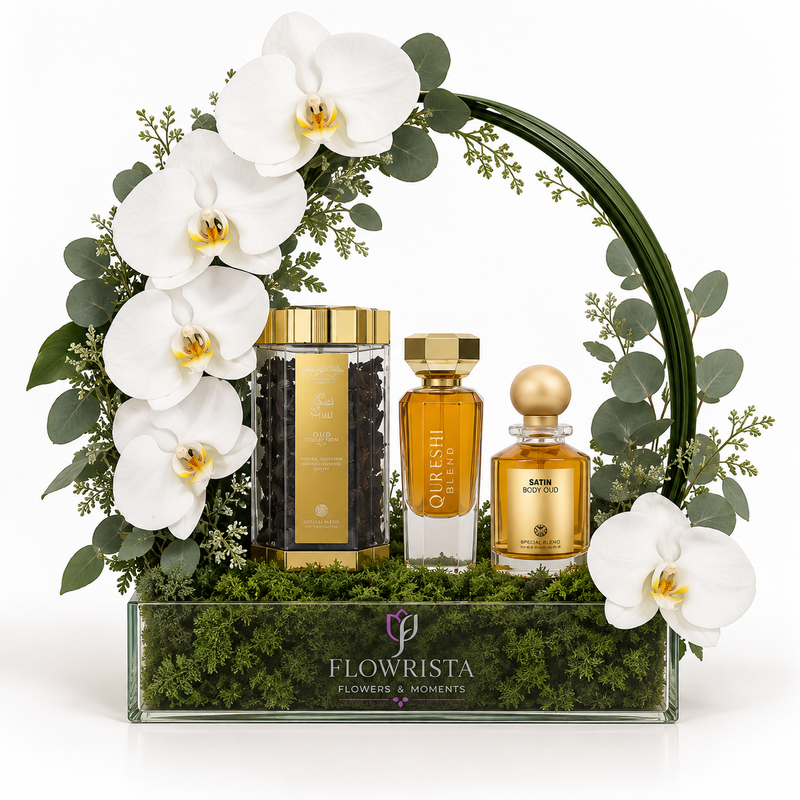 A luxury gift set from Flowrista featuring three fragrance and grooming products arranged in a clear glass tray filled with green moss, framed by white orchids and eucalyptus leaves on a white background.