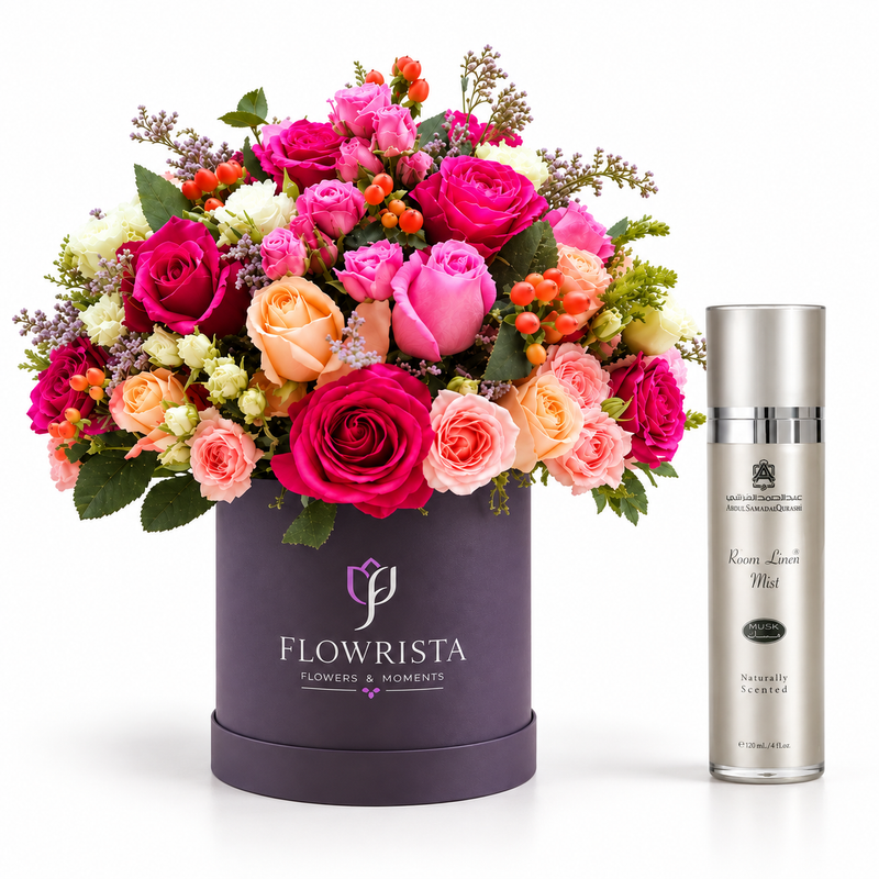 A vibrant floral arrangement in a dark purple round box with the brand name 'FLOWRISTA' printed on the front, displayed next to a silver bottle of 'Korean Limit Mist' on a clean white background.