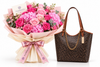A floral bouquet with pink and magenta flowers wrapped in blush pink paper and a cream ribbon printed with the FLOWRISTA brand name, shown beside a brown monogram tote bag with gold chain detail on a white background.