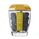 Clear container with gold lid and cardamom pods on a white background