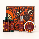 A gift set of Ajwa Date & Honey products arranged in front of a matching patterned box. The set includes a large amber bottle with a dark green cap, a smaller dark bottle with a green cap, a clear spray bottle with a silver cap, and a round tin with a matching label.